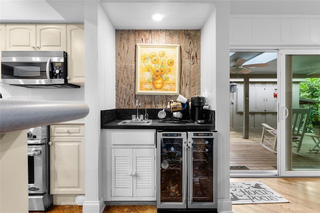 bar featuring sink, light hardwood / wood-style flooring, ceiling fan, white cabinetry, and wine cooler