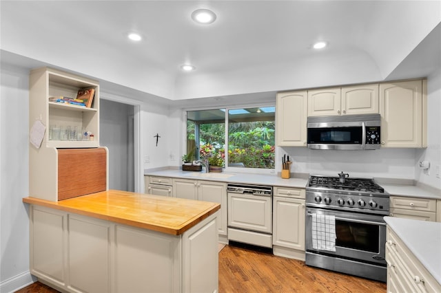 kitchen with stainless steel appliances, sink, wood counters, and light hardwood / wood-style floors