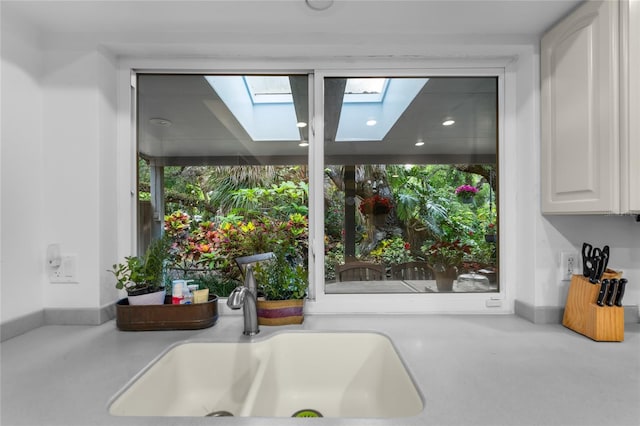 interior details with white cabinetry, sink, and a skylight