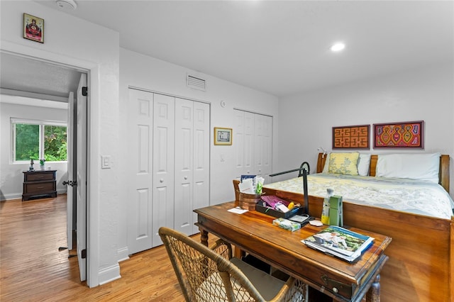 bedroom with multiple closets and light hardwood / wood-style flooring