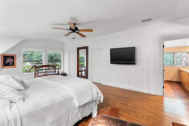 bedroom with wood-type flooring, vaulted ceiling, ensuite bathroom, and ceiling fan