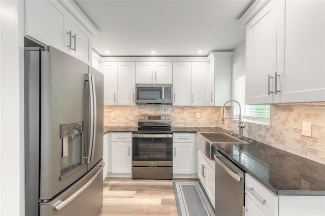 408 Wisteria Rd, Daytona Beach, FL 32118 - kitchen with sink, light wood-type flooring, appliances with stainless steel finishes, decorative backsplash, and white cabinets