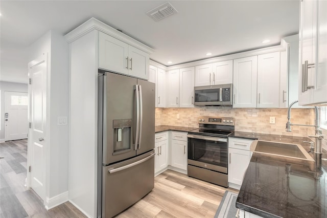408 Wisteria Rd, Daytona Beach, FL 32118 - kitchen with white cabinetry, sink, backsplash, and stainless steel appliances