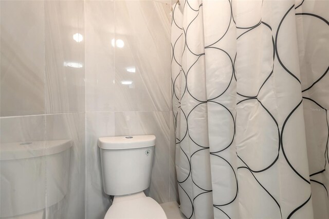 408 Wisteria Rd, Daytona Beach, FL 32118 - bathroom with toilet and tile walls