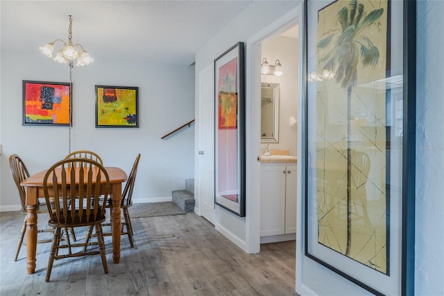 dining area featuring sink, a notable chandelier, and light hardwood / wood-style floors