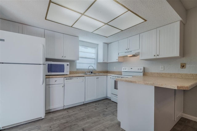 kitchen featuring sink, white appliances, white cabinetry, light hardwood / wood-style floors, and kitchen peninsula