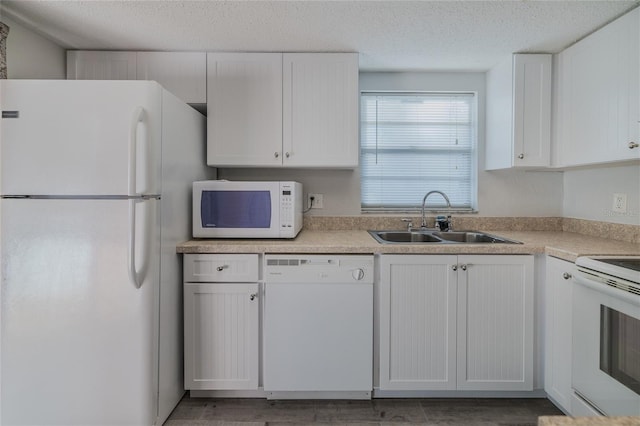 kitchen featuring white appliances, sink, a textured ceiling, and white cabinets