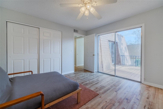 bedroom with ceiling fan, a textured ceiling, access to outside, a closet, and light wood-type flooring