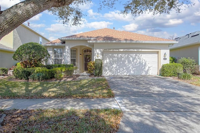 view of front of property featuring a garage, roof with shingles, concrete driveway, and stucco siding