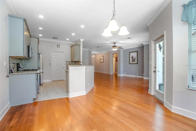 kitchen with decorative backsplash, appliances with stainless steel finishes, open floor plan, ornamental molding, and ceiling fan with notable chandelier