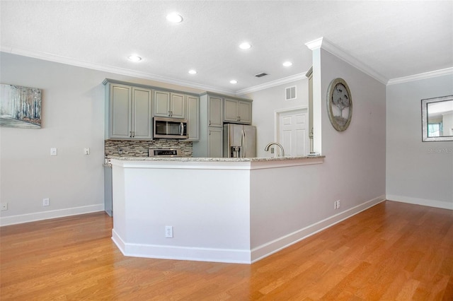 kitchen featuring visible vents, appliances with stainless steel finishes, a peninsula, gray cabinets, and backsplash