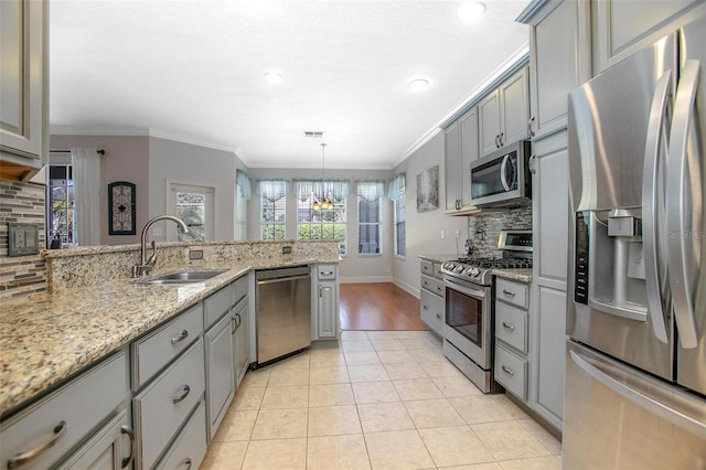 kitchen featuring light tile patterned floors, appliances with stainless steel finishes, hanging light fixtures, gray cabinets, and a sink