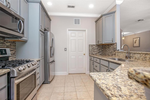 kitchen featuring appliances with stainless steel finishes, visible vents, a sink, and light stone countertops