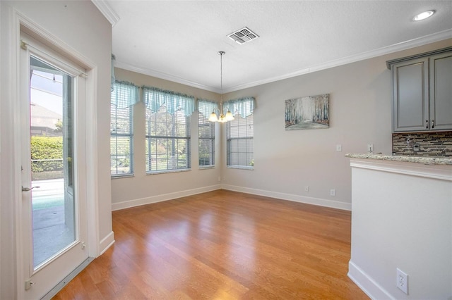 unfurnished dining area featuring light wood-style floors, visible vents, ornamental molding, and baseboards