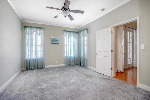 carpeted spare room with baseboards, ornamental molding, ceiling fan, and french doors