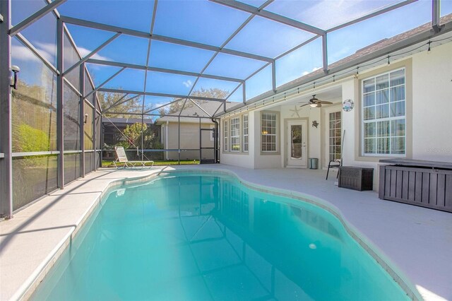 outdoor pool featuring ceiling fan, glass enclosure, and a patio area