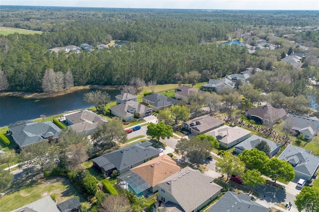 drone / aerial view featuring a residential view, a water view, and a view of trees