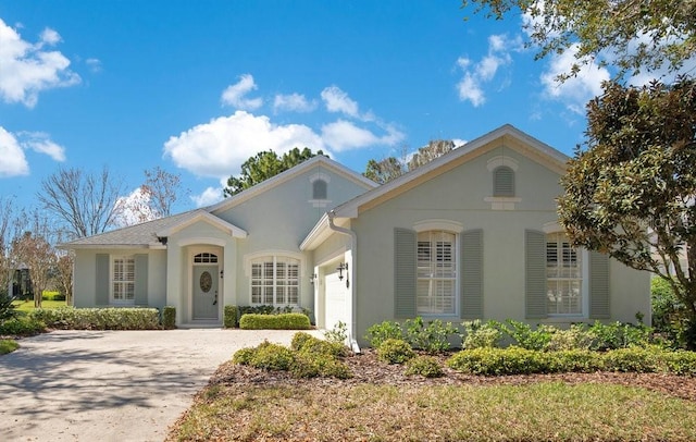 view of front of property with an attached garage, driveway, and stucco siding