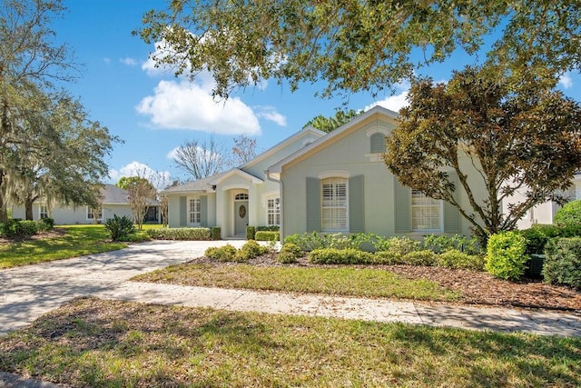 view of front facade with a front yard, concrete driveway, and stucco siding