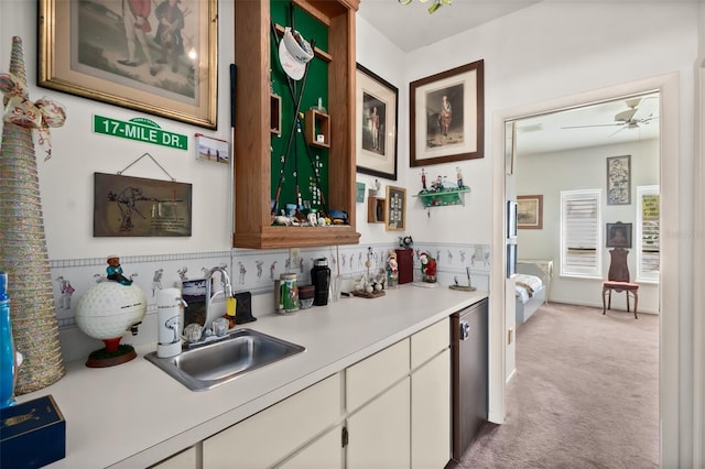 bar with sink, light colored carpet, ceiling fan, white cabinets, and stainless steel dishwasher