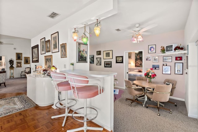 kitchen with parquet flooring, a breakfast bar, pendant lighting, ceiling fan, and kitchen peninsula