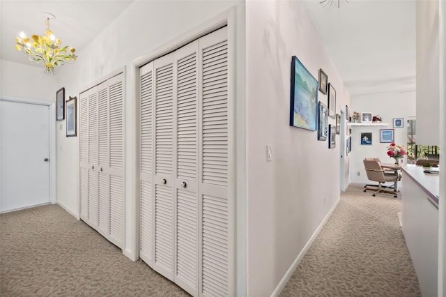 corridor with light colored carpet and a chandelier