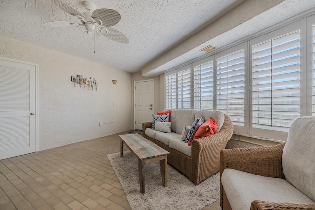 living room with ceiling fan, a textured ceiling, and a wealth of natural light