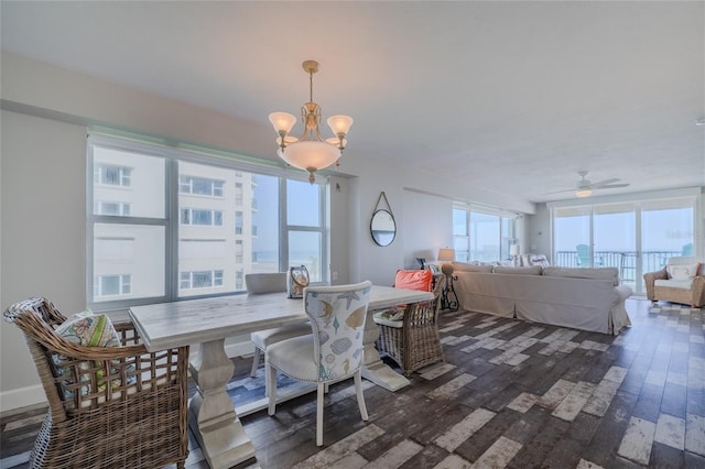 dining area featuring dark wood-type flooring and ceiling fan with notable chandelier