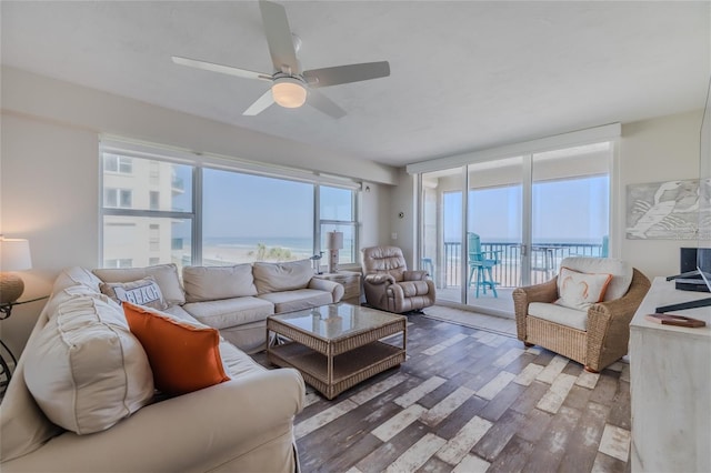 living room featuring hardwood / wood-style flooring, ceiling fan, and a water view