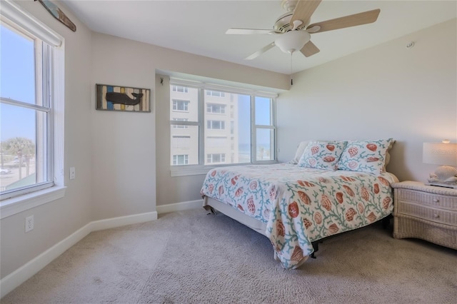 bedroom featuring multiple windows, light carpet, and ceiling fan