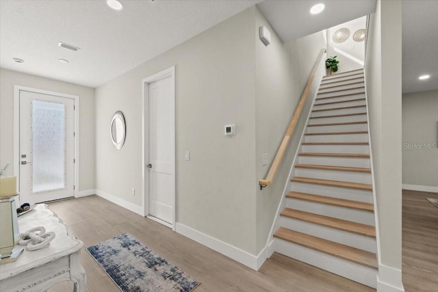 foyer entrance with light hardwood / wood-style flooring and a textured ceiling