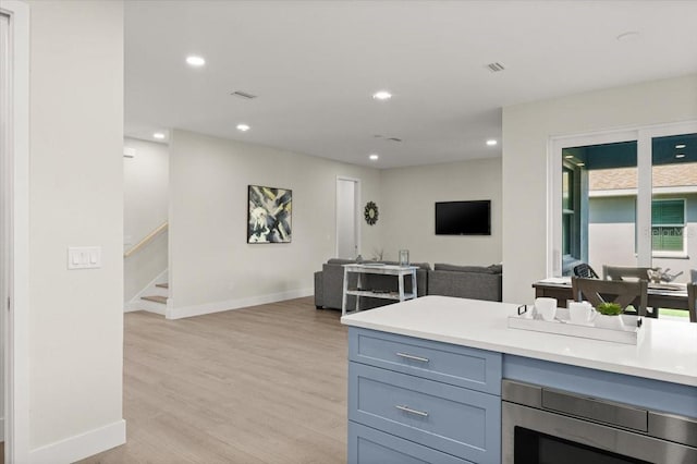 kitchen with stainless steel microwave and light hardwood / wood-style floors