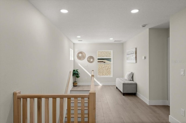 hall with light hardwood / wood-style flooring and a textured ceiling