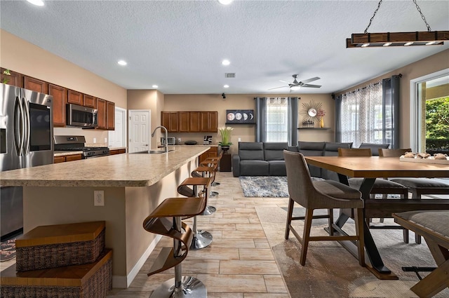 kitchen featuring appliances with stainless steel finishes, sink, a kitchen island with sink, and a kitchen bar