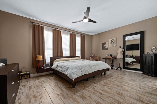 bedroom with ceiling fan, a textured ceiling, and light hardwood / wood-style floors