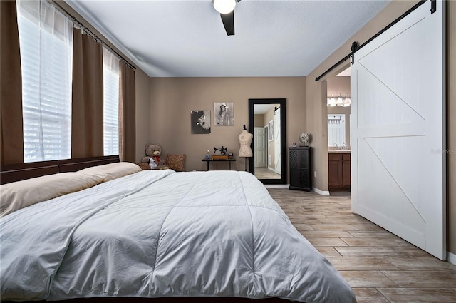 bedroom featuring a barn door, connected bathroom, a textured ceiling, and ceiling fan