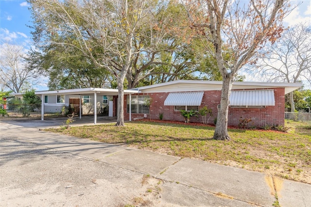 ranch-style house featuring a front lawn and a carport