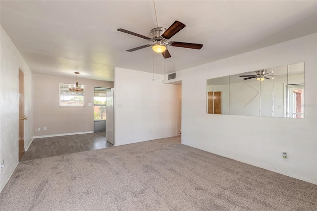 carpeted empty room with ceiling fan with notable chandelier