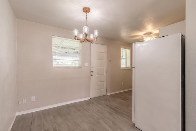 unfurnished dining area featuring a notable chandelier and wood-type flooring