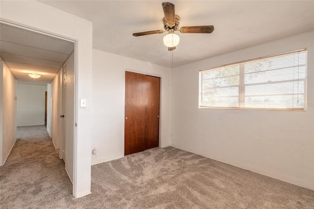 unfurnished bedroom featuring ceiling fan, light colored carpet, and a closet