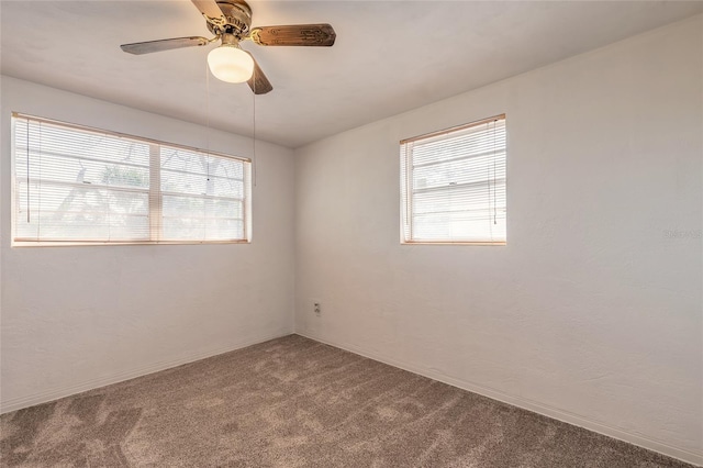 carpeted spare room featuring ceiling fan and a wealth of natural light