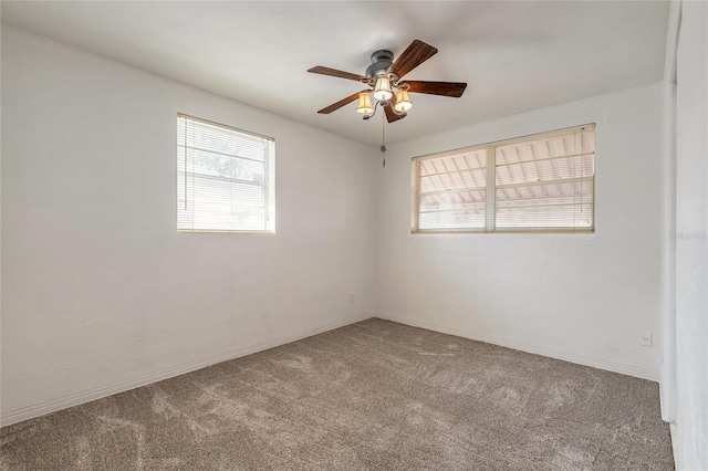 carpeted empty room with ceiling fan and a wealth of natural light