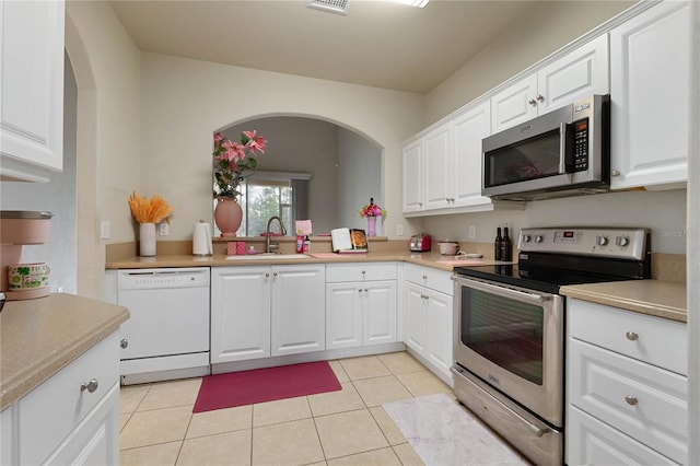 kitchen featuring sink, light tile patterned floors, appliances with stainless steel finishes, white cabinets, and kitchen peninsula