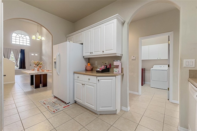 kitchen with light tile patterned flooring, a notable chandelier, washer / clothes dryer, white refrigerator with ice dispenser, and white cabinets