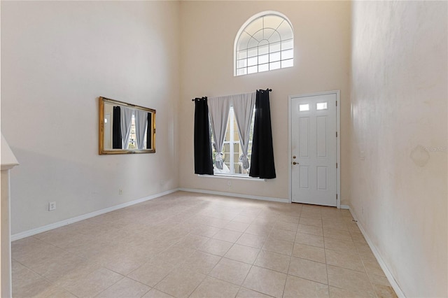 entryway featuring light tile patterned floors, plenty of natural light, and a high ceiling