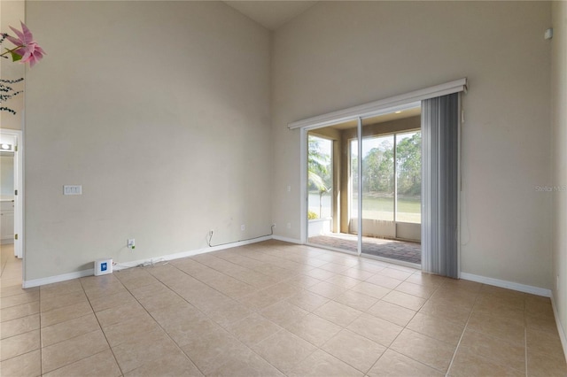 tiled spare room with a towering ceiling