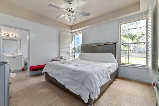 bedroom with ceiling fan, light colored carpet, and ensuite bath