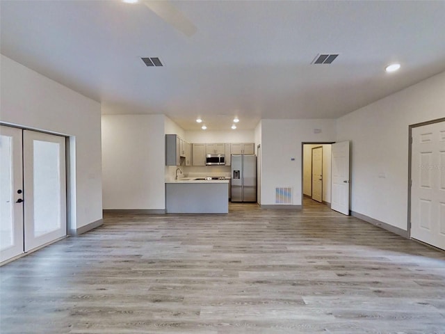 unfurnished living room with visible vents, light wood-style flooring, and baseboards