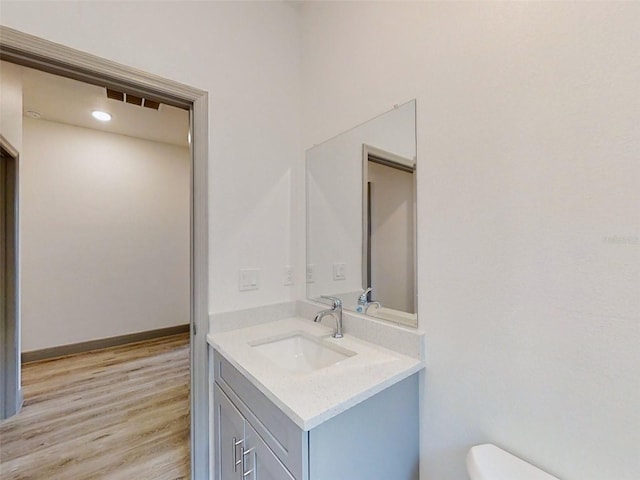 bathroom featuring vanity, baseboards, toilet, visible vents, and wood finished floors