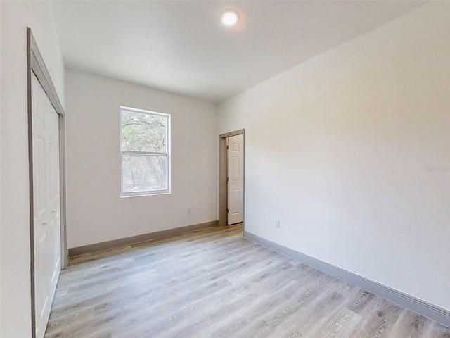 unfurnished bedroom featuring a closet, light wood finished floors, and baseboards